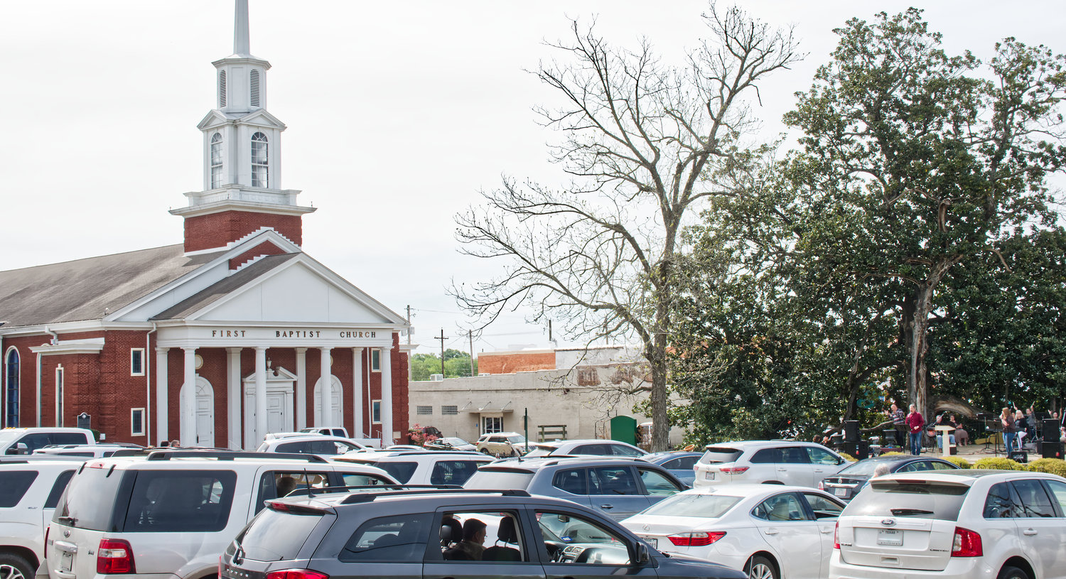 Dozens of churchgoers gathered in the parking lot across from their usual meeting place at the First Baptist Church in Mineola on Sunday, March 29, practicing social distancing while singing from their vehicles, led by an amplified praise team at Peterson Park.